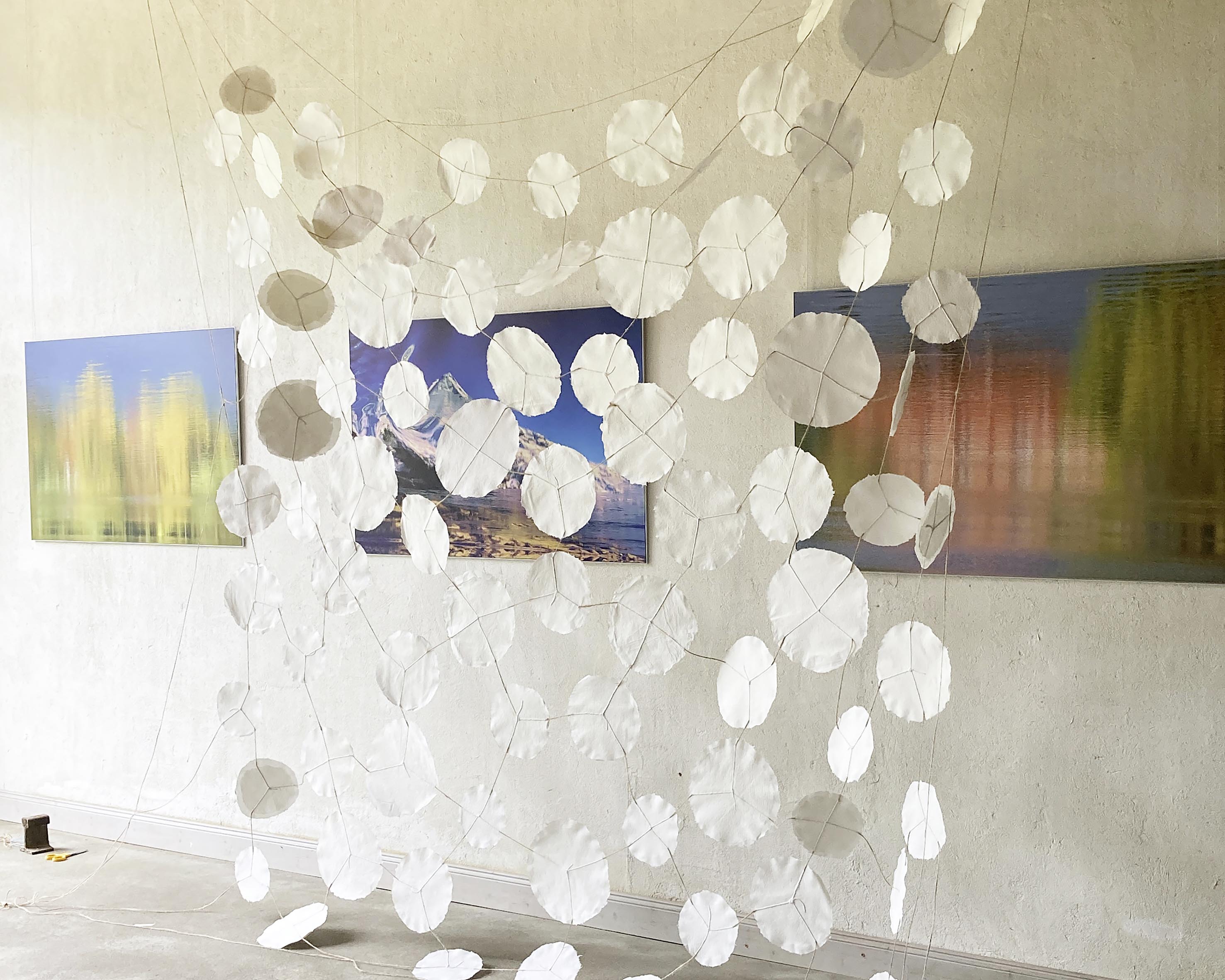 Anke Meixner: 82. 2025, handgeschöpftes Papier, Schnur, vor Fotos von Ulrich Rudolph